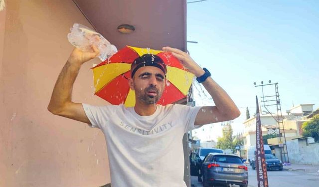 Aşırı sıcaklar nedeniyle kafasına taktığı şemsiye ile geziyor